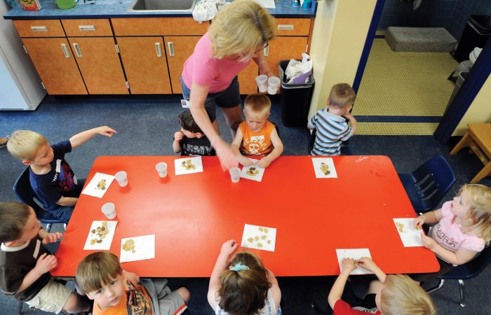 In this May 11, 2011 photo, teacher Kristie Niebeling hands out snacks to children during an Early Childhood Family Education program in Waconia, Minn. The district's elementary schools are so packed, they had to create space in one of the district warehouses for early childhood classes. (AP Photo/Craig Lassig)